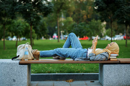 Arab female student lying on the bench in parkの写真素材