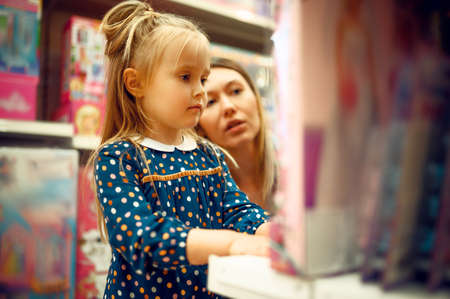 Mother and little girl choosing a doll, toy storeの写真素材
