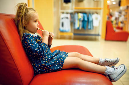 Little girl sitting on sofa in childrens shopの写真素材