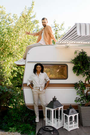 Happy couple poses near rv, camping in a trailer