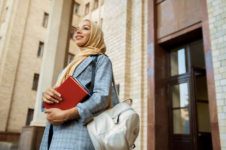 Arab girl with books poses at university entranceの写真素材