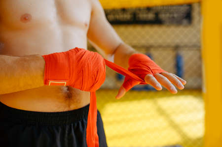 MMA fighter wraps bandages on his hands in gymの写真素材