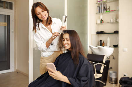 Hairdresser straightens womans hair, hairsalonの写真素材