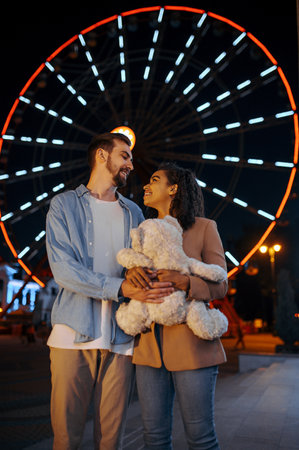 Love couple with soft toy in night amusement parkの写真素材