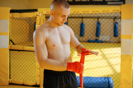 MMA fighter wraps bandages on his hands in gym