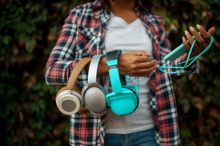 Female music fan holds headphones in summer parkの写真素材