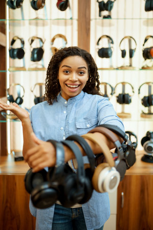 Woman shows headphones collection in audio storeの写真素材