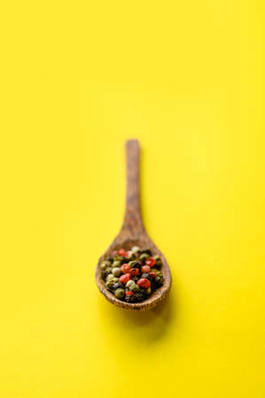 Spices in a spoon closeup, yellow background