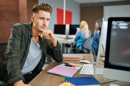 Thoughtful male IT specialist sits at the table