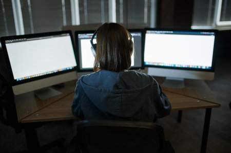 Female hacker in headphones works on computerの写真素材
