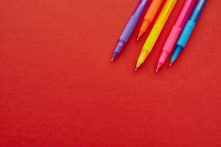 Colorful pens with caps closeup, red backgroundの写真素材