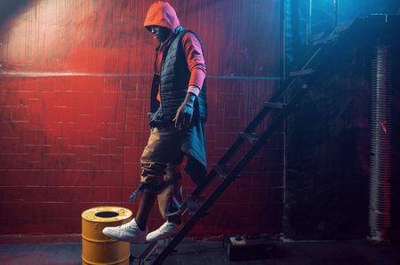 Stylish rapper in hoodie poses in grunge studioの写真素材