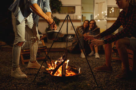 Friends warming themselves by campfire, camping