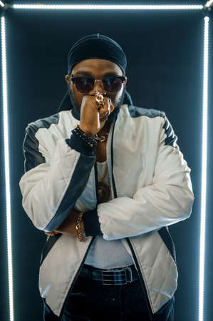 Stylish rapper in sunglasses, dark background