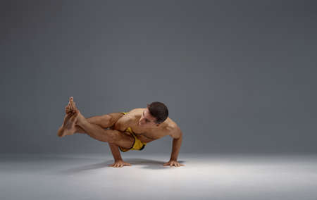Male yoga in a difficult pose on hands, meditation