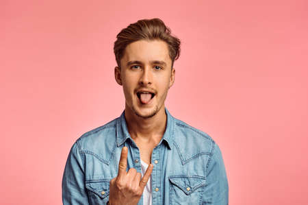 Man shows his tongue, pink background, emotion
