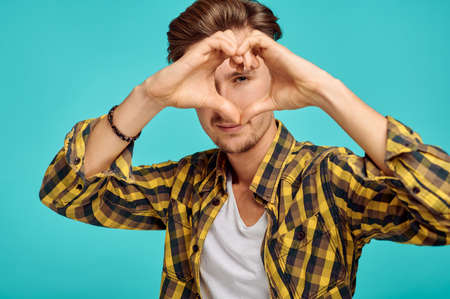 Young man shows heart sign, blue backgroundの写真素材