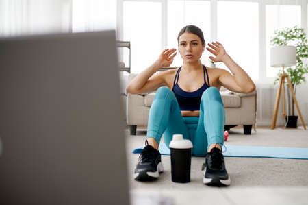 Woman sits on mat, online fitness training