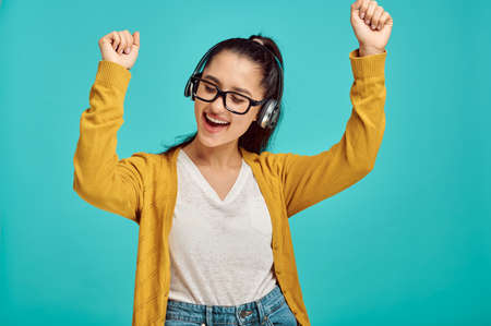 Happy young woman in headphones, blue backgroundの写真素材