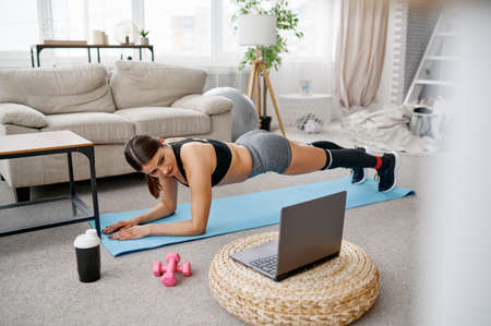 Smiling girl sits on floor, online fit trainingの写真素材