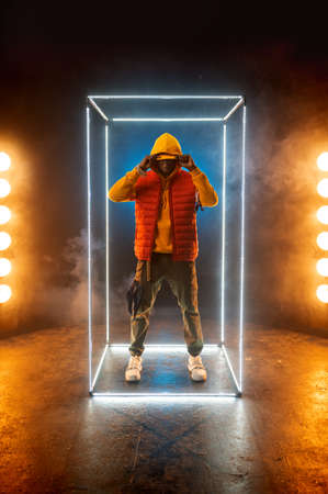 Stylish rapper poses in illuminated cube