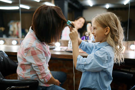 Mother and daughter straighten hairstyles in salonの写真素材