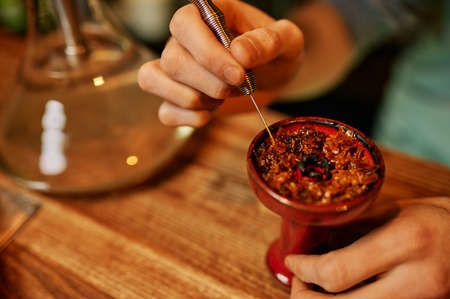 Hookah maker prepares hooka for smoking in barの写真素材