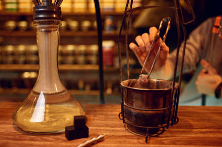 Male hookah maker, coal preparation in barの写真素材