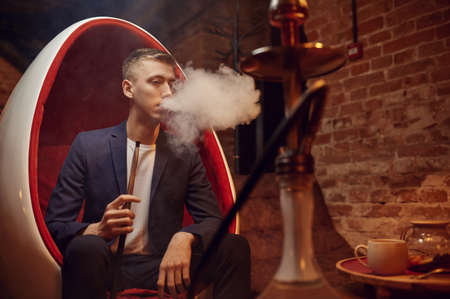 Young man smokes in hookah bar, hooka chill outの写真素材