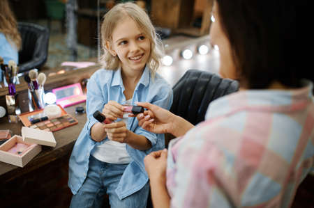Mother gives daughter nail polish, makeup artistsの写真素材