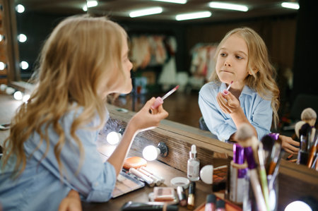 Little girl using lipstick in makeup salonの写真素材