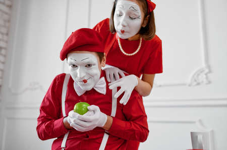 Two mime artists in red costumes, scene with appleの写真素材