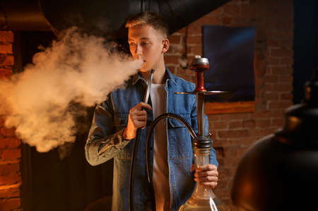 Young man blows smoke in hookah bar, hookaの写真素材