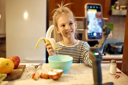 Girl with banana makes food blog, child bloggerの写真素材