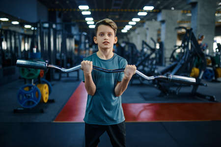 Youngster doing exercise with bar in gymの写真素材