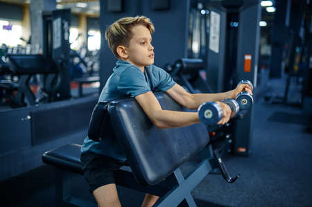 Teenager doing exercise with dumbbells in gymの写真素材