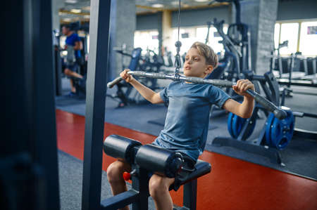 Boy on exercise machine, training in gymの写真素材