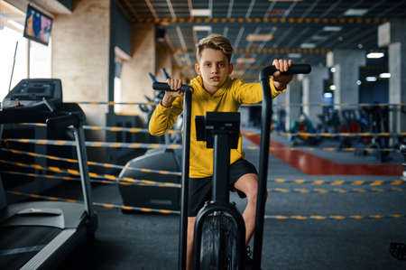 Child on exercise machine, training in gym