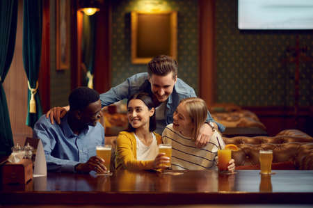 Four friends drinks alcohol at the counter in barの写真素材