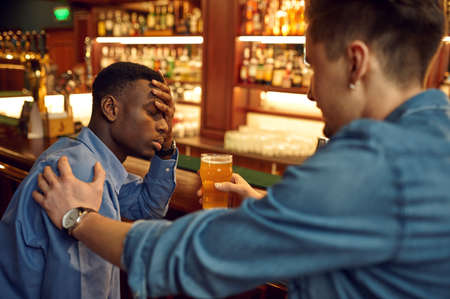 Male friends drinks beer at the counter in barの写真素材
