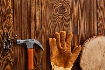 Screw nails, hammer and glove on wooden backgroundの写真素材