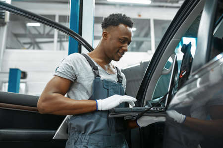 Male mechanic using laptop, car service