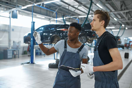 Two male mechanics talking in car service