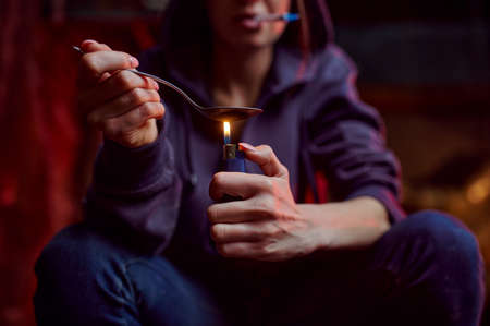 Drug addict with spoon and fire prepares doseの写真素材