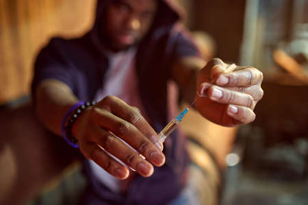 Drug addict man holds syringe with doseの写真素材