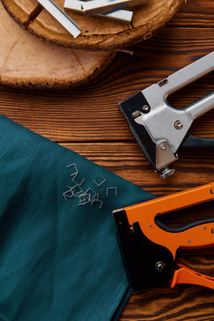 Stapler and staples on stump, wooden background