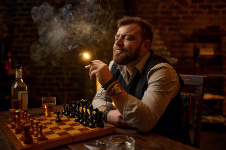 Man smokes a cigar, smoker leisures at chessboardの写真素材