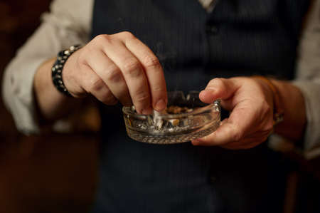 Man puts out a cigarette in ashtray, closeup view