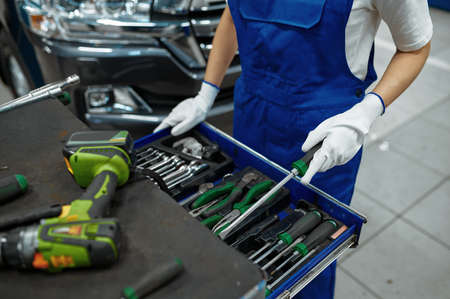 Female worker stands at the toolbox, car service