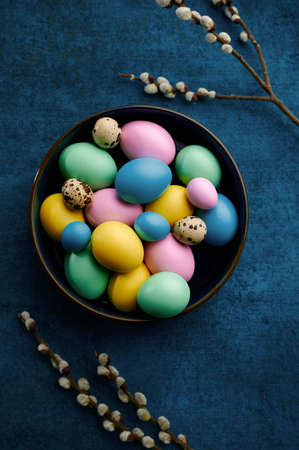 Blooming willow branch and easter eggs in bowlの写真素材